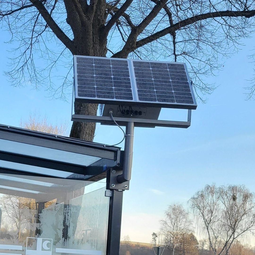 Solarmodul auf einem Gestell, montiert an einem Buswartehäuschen im Freien.
